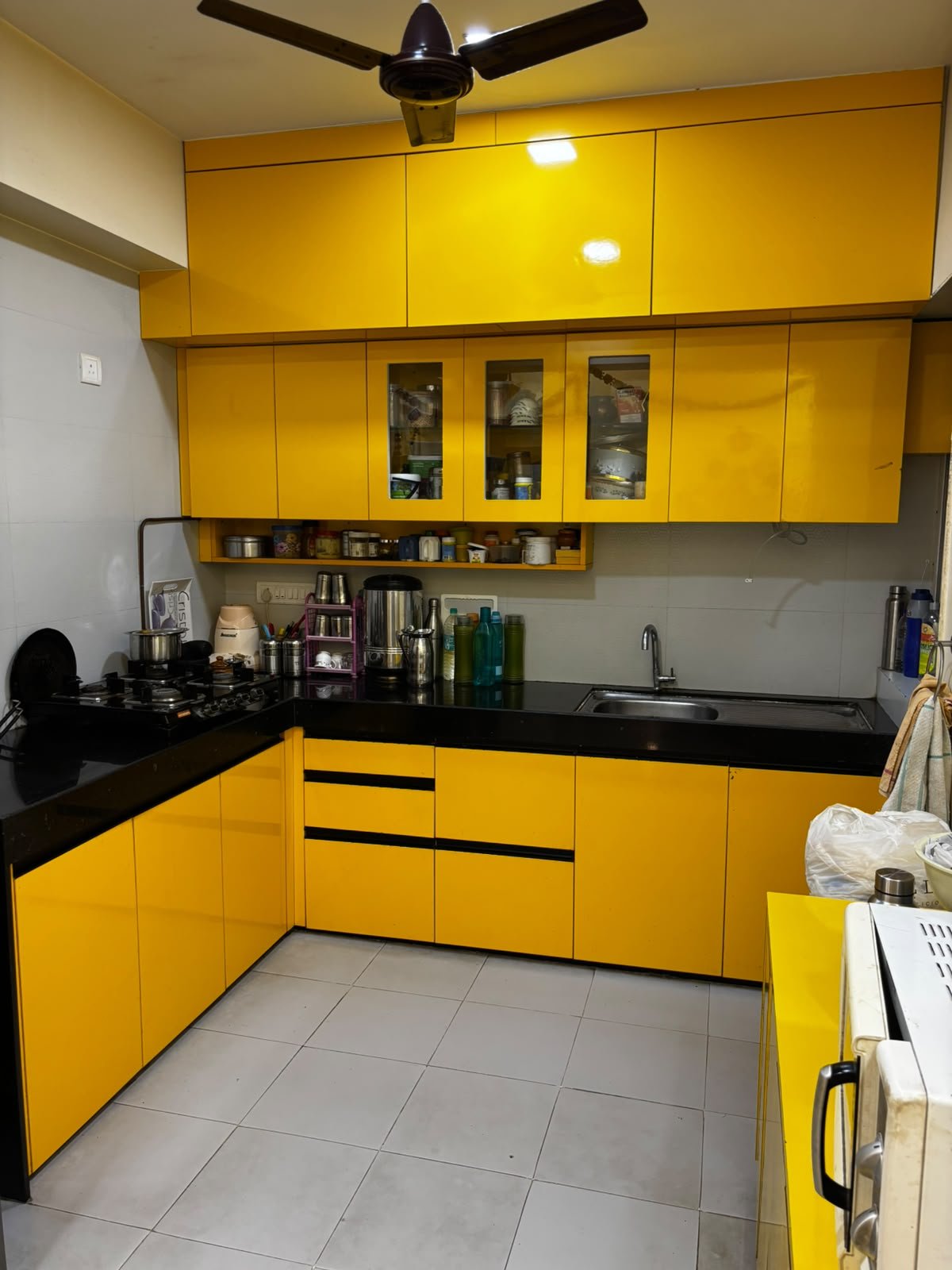 Yellow modular kitchen with black countertop and fitted cabinets